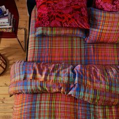 a bed with colorful plaid sheets and pillows