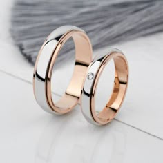 two gold wedding rings with diamonds on the inside and outside, sitting next to each other