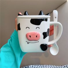 a person holding a coffee mug with a cow face on it