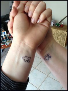 two people with matching tattoos on their wrists holding hands and one has a puzzle piece tattooed on the wrist