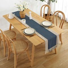 a wooden table topped with plates and cups next to a vase filled with flowers on top of a hard wood floor