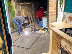 a man working on a piece of metal in a garage with tools and other items