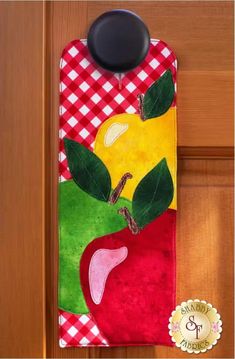 an apple door hanger on a wooden door with a checkered red and white table cloth