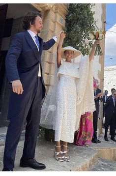 a man in a suit and tie standing next to a woman wearing a white dress