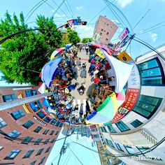 a fish - eye view of people standing in the middle of a street with buildings and trees