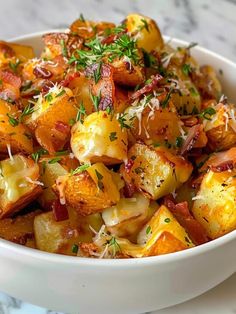 a white bowl filled with potatoes covered in parmesan cheese and topped with herbs