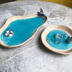 two ceramic bowls with rings on them sitting on a marble table next to each other