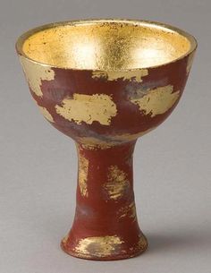 an old red and gold cup with white spots