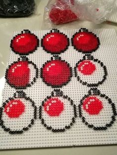 some red and black beads are on a white table top with plastic bags in the background