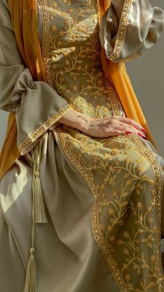 a woman is dressed in an elaborately designed dress and holding her hand on her hip