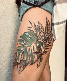 a woman's leg with a tattoo on it that has leaves and plants on it