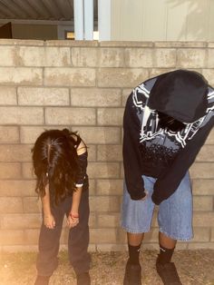 two people standing in front of a brick wall