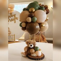 a teddy bear sitting on top of a table with balloons in the shape of animals