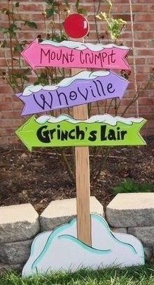 a wooden sign sitting on top of a lush green grass covered park bench next to a brick wall