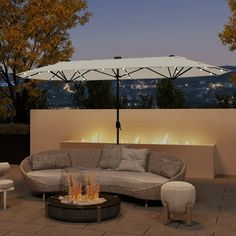 an outdoor fire pit and seating area with umbrellas over the firepit at night