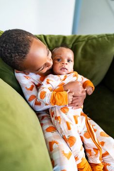 a woman holding a baby on top of a green couch