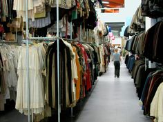 there is a man walking down the aisle of a clothing store