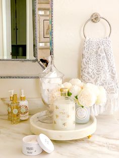 a bathroom counter with flowers and personal care items on it, along with a mirror