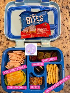 a blue lunch box filled with different types of snacks and crackers on top of it