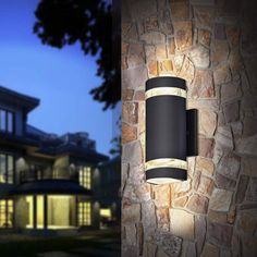 an outdoor wall light that is on the side of a building at night and in front of a house