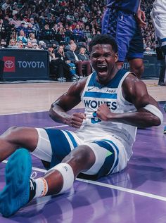 a man sitting on top of a basketball court with his foot up in the air