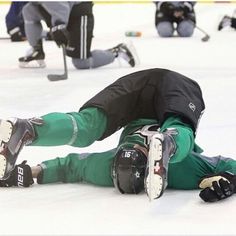 a man laying on the ice while wearing green pants