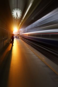 a person standing in a train station with a clock on the wall