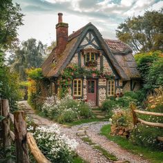 an old cottage with flowers growing on the windows and door, surrounded by greenery