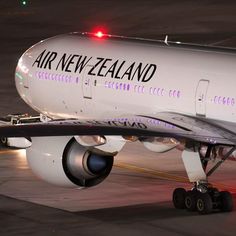 an air new zealand airplane is parked on the tarmac at night with its lights on