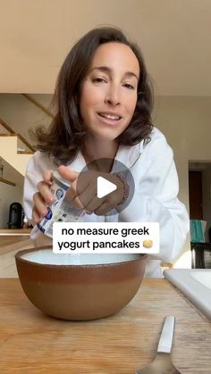 a woman holding a can of yogurt in front of a bowl