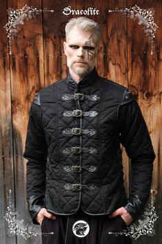 a man with white hair wearing a black jacket and standing in front of a wooden wall