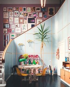 a room with pictures on the wall and a table in front of a stair case