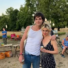 a man and woman standing next to each other in front of people at an outdoor event