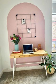 a laptop computer sitting on top of a wooden desk next to a potted plant