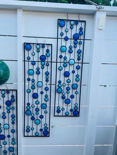 a white fence with blue glass balls on it and a green vase sitting next to it