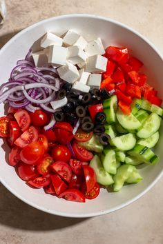 a white bowl filled with sliced vegetables and diced cheese