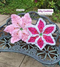 two crocheted flowers sitting on top of a metal bench