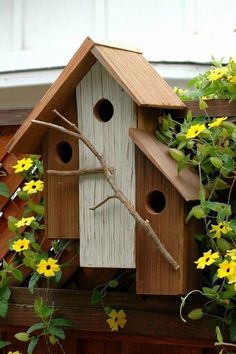 a bird house with yellow flowers in the background