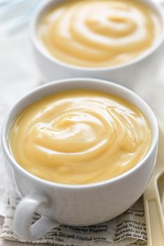 two white bowls filled with soup sitting on top of a table