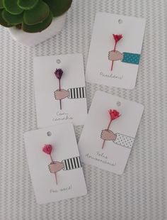 four small tags with flowers on them sitting next to a potted succulent