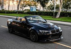 a black bmw convertible parked on the side of the road