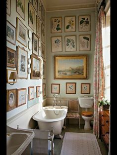 a bath room with a tub a toilet and pictures on the wall