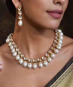 Be the divine bliss of beauty with this Gold Toned White Handcrafted Brass Kundan Necklace with Earrings Set. It is an intricately handcrafted brass Kundan necklace with pearl detailing that comes with a pair of matching earrings. Elegant Brass Kundan Chandbali Necklace, Elegant Kundan Chandbali Necklace In Brass, Elegant Chandbali Kundan Necklace In Brass, Brass Jewelry With Pearl Charm For Weddings, Elegant Chandbali Bridal Necklace In Brass, Elegant Brass Jewelry Sets For Festivals, Celebration Pearl Necklace For Diwali, Diwali Celebration Pearl Necklace, Kundan Necklace With Pearl Chain For Celebration