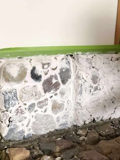 a green bench sitting on top of a stone floor next to a white brick wall