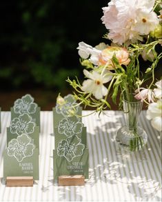 the table is set up with place cards and flowers in vases on top of it