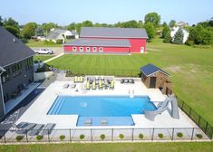 an aerial view of a house with a swimming pool in the foreground and a red barn in the background