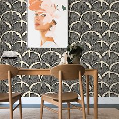 two chairs and a table in front of a wall with art deco artwork on it