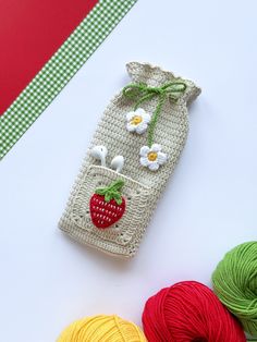 a crocheted bag with flowers and strawberries on it next to balls of yarn