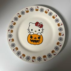 a hello kitty plate with pumpkins and skulls on the front, sitting on a white surface