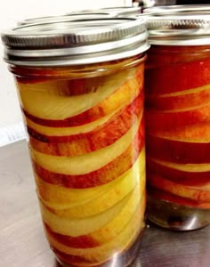 two jars filled with sliced apples sitting on top of a table